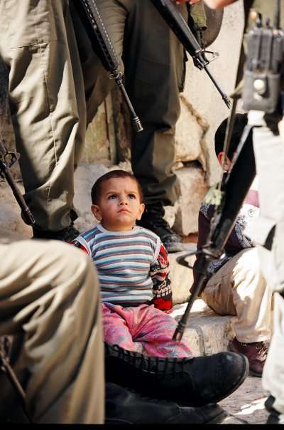 Young Palestinian boy surrounded by armed IDF soldiers